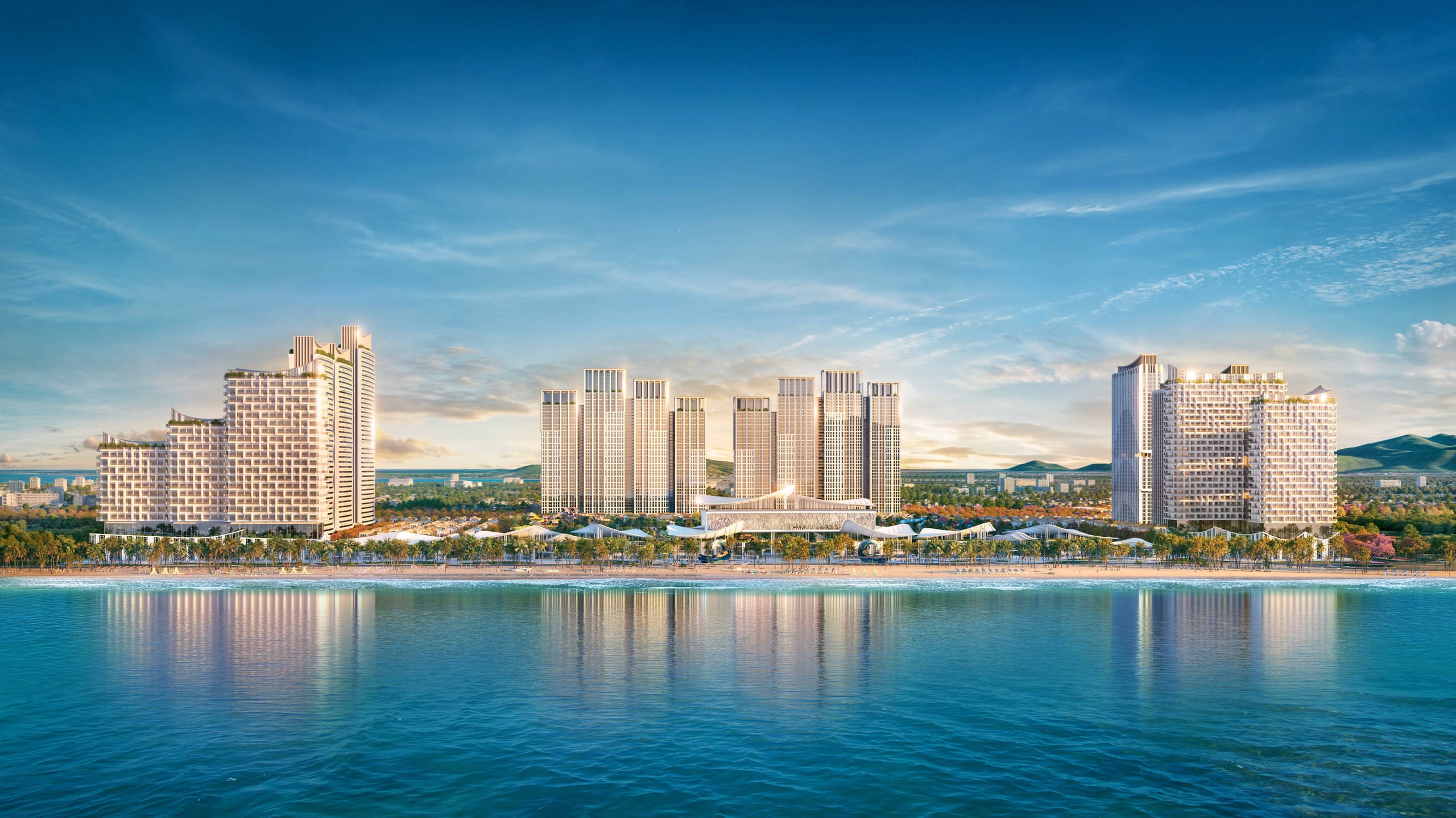 Modern high-rise residential buildings at Blanca City by Sun Group along the waterfront with scenic mountain views in the background.